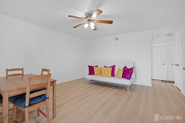 living area with light wood-style floors, baseboards, visible vents, and a ceiling fan