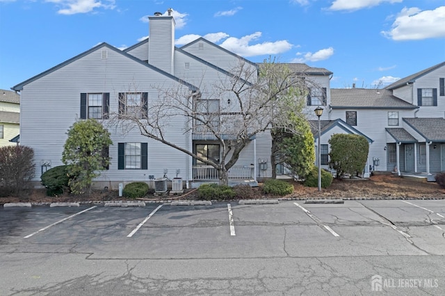 view of property with uncovered parking and central AC