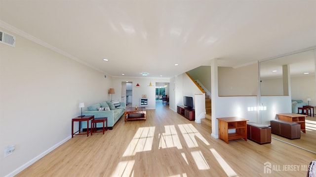 interior space with visible vents, light wood-style flooring, baseboards, and ornamental molding