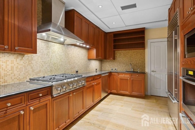 kitchen with dark stone counters, tasteful backsplash, sink, wall chimney range hood, and stainless steel appliances