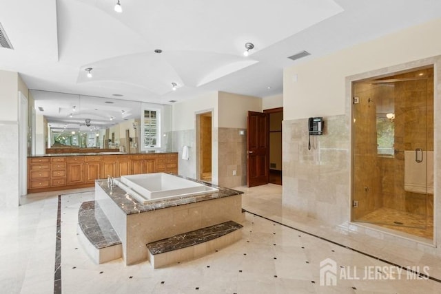 bathroom featuring tile walls, independent shower and bath, and vanity