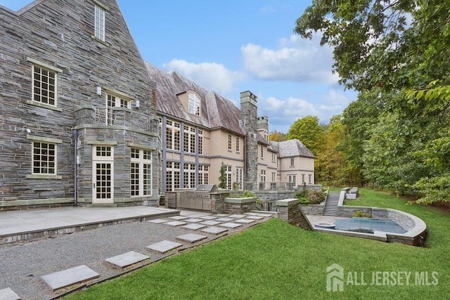 back of property with an outdoor kitchen, a yard, and a patio area