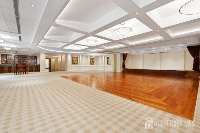 workout room featuring coffered ceiling and wood-type flooring