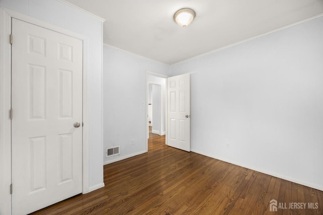 unfurnished bedroom with wood finished floors, visible vents, baseboards, and ornamental molding