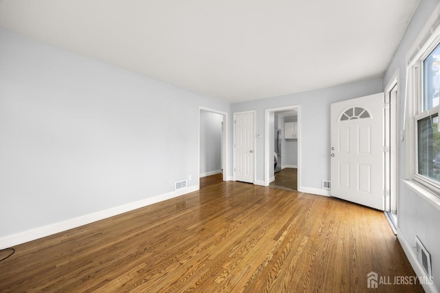 interior space with baseboards, wood finished floors, and visible vents