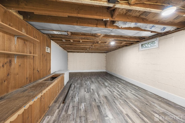 basement featuring dark wood finished floors, baseboards, and visible vents