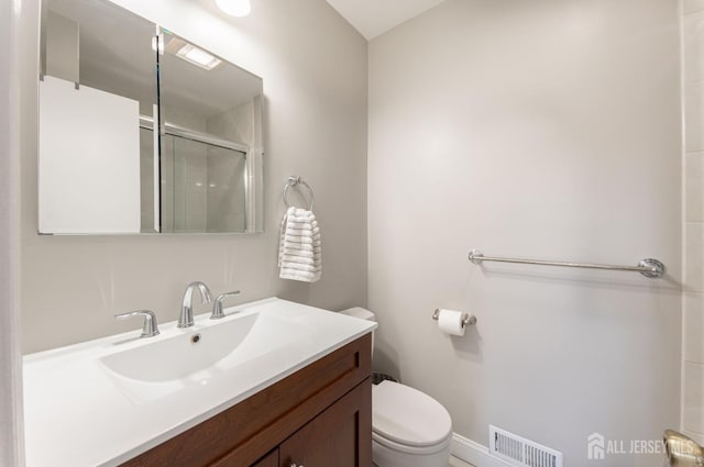 bathroom with vanity, toilet, visible vents, and a stall shower