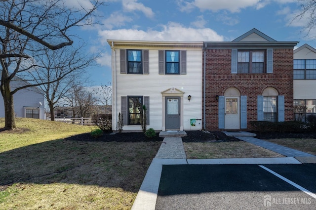 view of front of home featuring brick siding, uncovered parking, and a front lawn