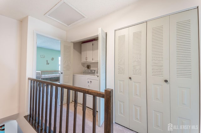 corridor with an upstairs landing, separate washer and dryer, and attic access