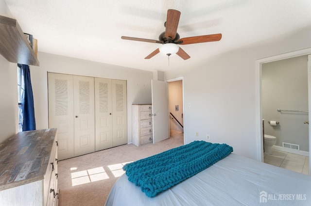 bedroom featuring visible vents, ceiling fan, light carpet, ensuite bathroom, and a closet