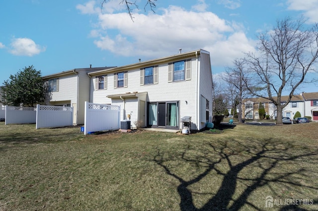 rear view of house featuring fence and a lawn