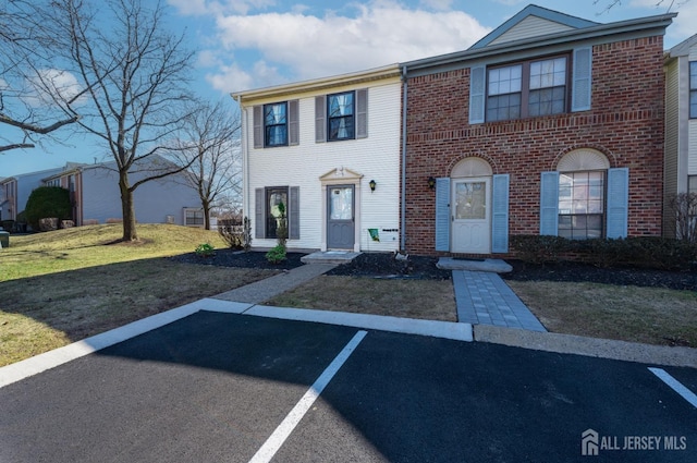 view of front of property featuring a front yard, uncovered parking, and brick siding