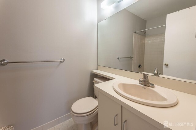 full bathroom featuring toilet, tile patterned flooring, baseboards, walk in shower, and vanity