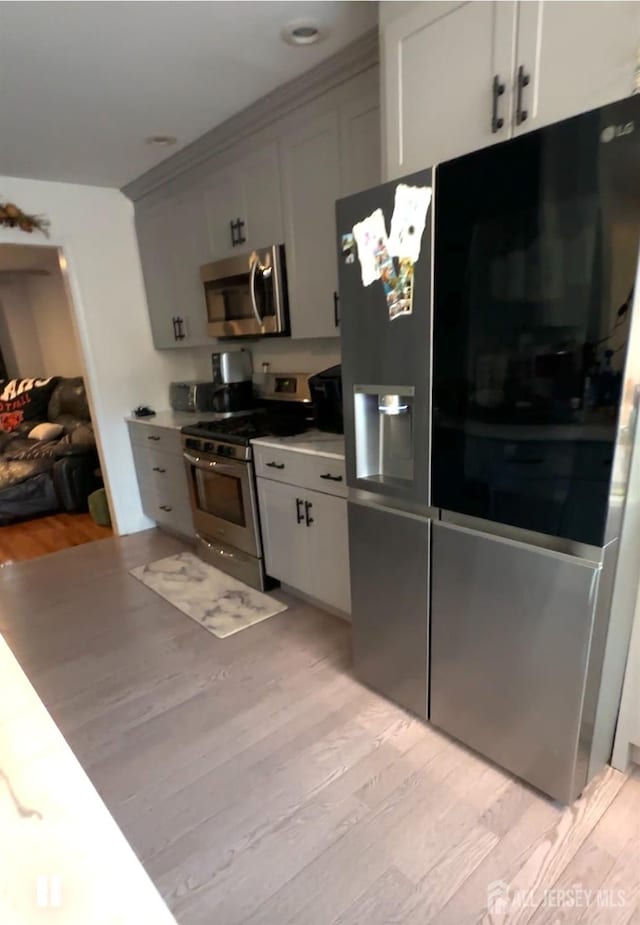 150 School St, Piscataway, NJ 08878 - kitchen with stainless steel appliances, light wood-type flooring, white cabinetry, and light countertops