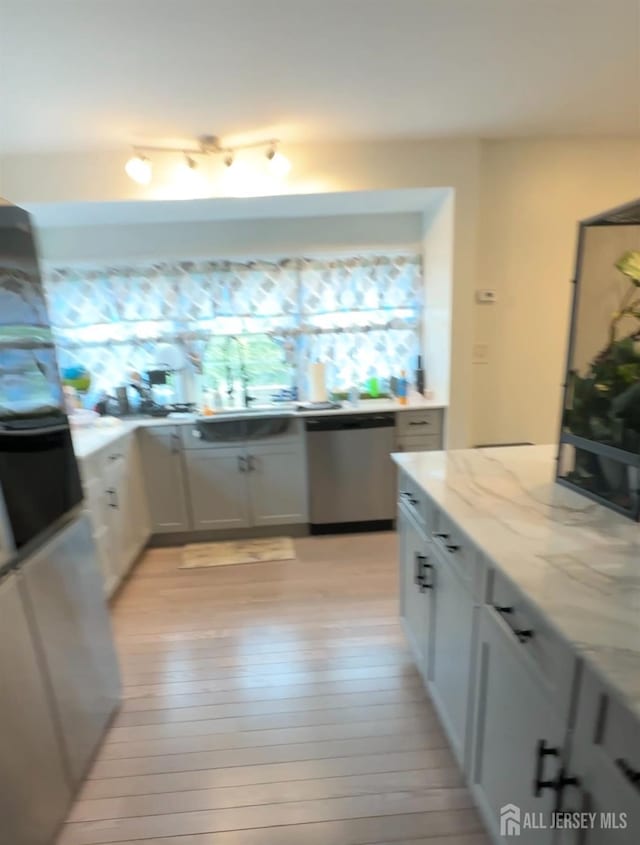 150 School St, Piscataway, NJ 08878 - kitchen featuring stainless steel dishwasher, light stone counters, light wood-style floors, and white cabinets