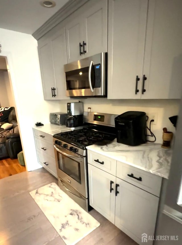 150 School St, Piscataway, NJ 08878 - kitchen featuring stainless steel appliances, light wood-type flooring, and light stone countertops