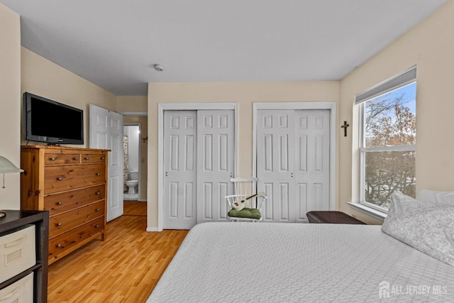 bedroom with light wood-style flooring and two closets