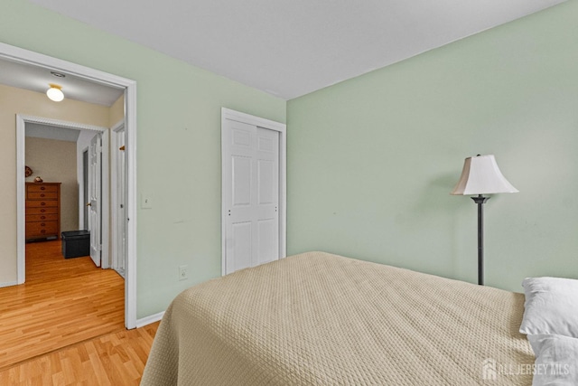 bedroom with a closet, baseboards, and wood finished floors