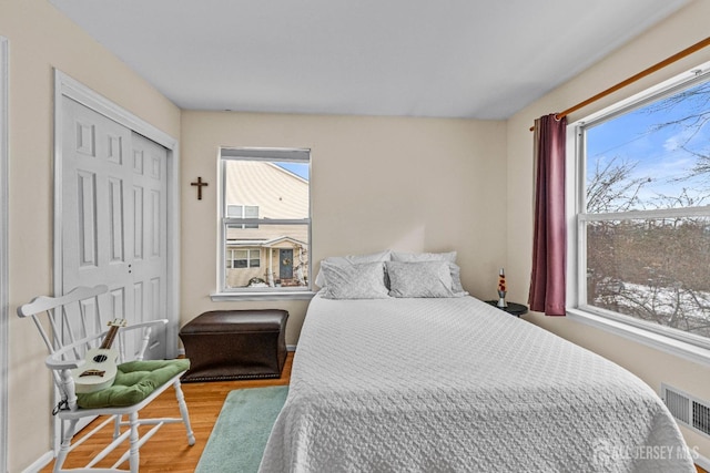 bedroom featuring a closet, wood finished floors, visible vents, and baseboards