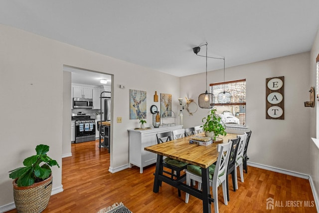 dining space with baseboards and light wood finished floors