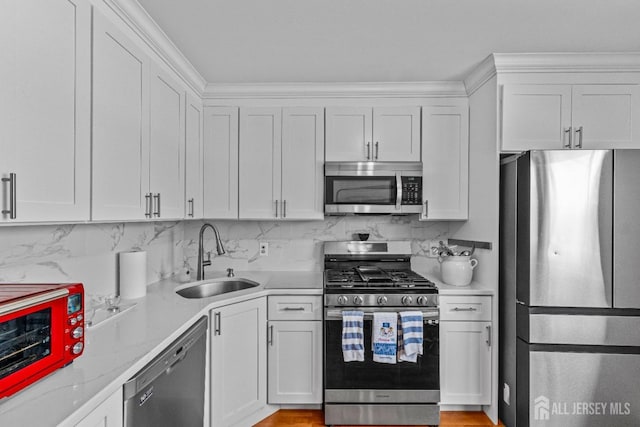 kitchen with white cabinetry, appliances with stainless steel finishes, tasteful backsplash, and a sink