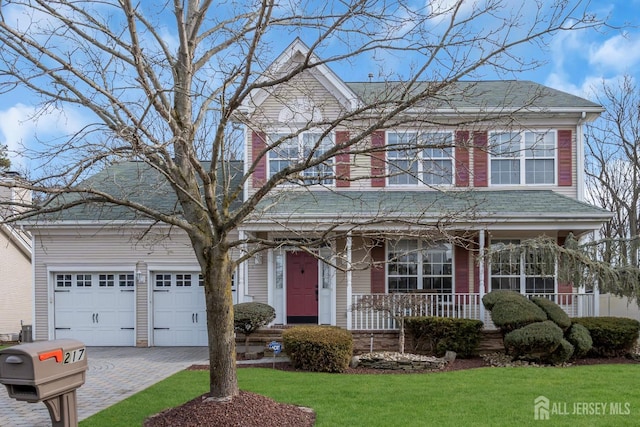 view of front facade featuring covered porch, decorative driveway, a front yard, and an attached garage