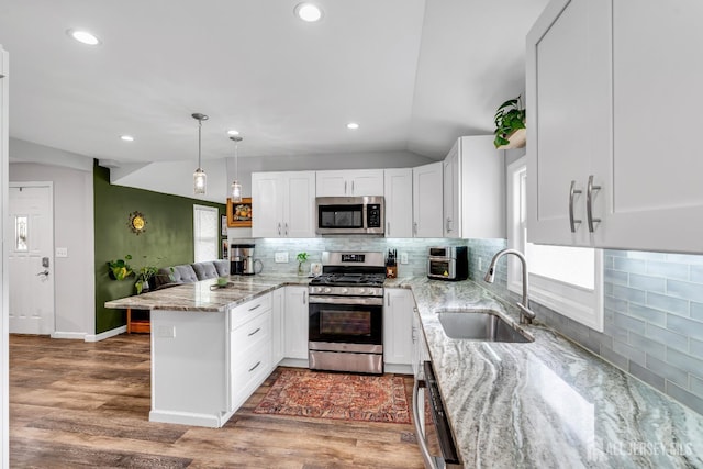 208 Hilltop Blvd, Old Bridge, NJ 07735 - kitchen with appliances with stainless steel finishes, a peninsula, vaulted ceiling, white cabinetry, and backsplash