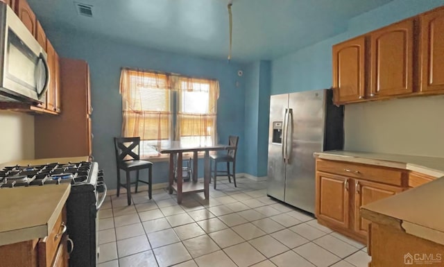 264 Seaman St, New Brunswick, NJ 08901 - kitchen with appliances with stainless steel finishes, light countertops, light tile patterned floors, and brown cabinetry