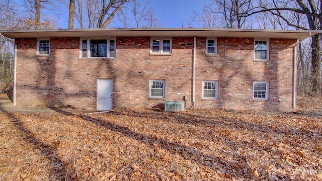 view of side of home with cooling unit and brick siding