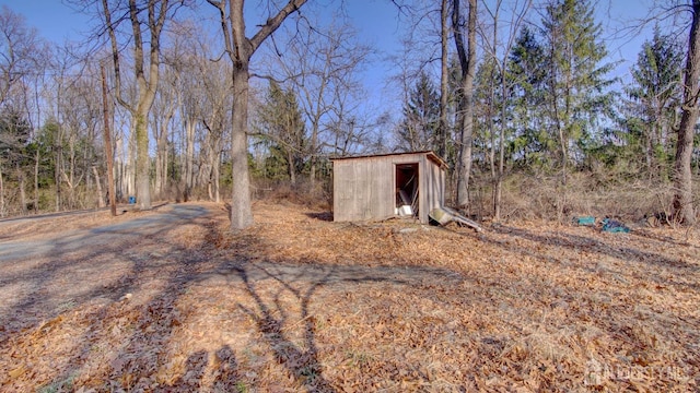 view of yard with a forest view, a storage unit, and an outdoor structure