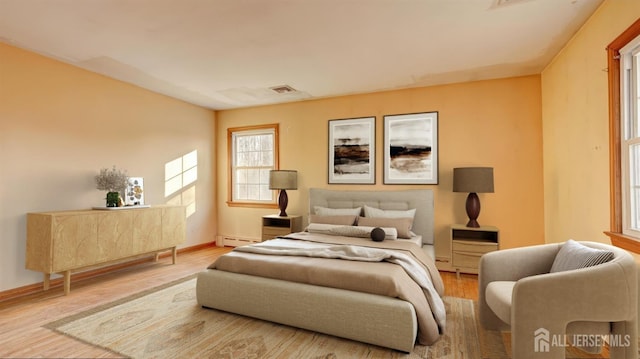 bedroom featuring baseboard heating, baseboards, visible vents, and wood finished floors