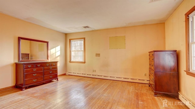 empty room featuring visible vents, hardwood / wood-style flooring, a baseboard heating unit, baseboards, and baseboard heating