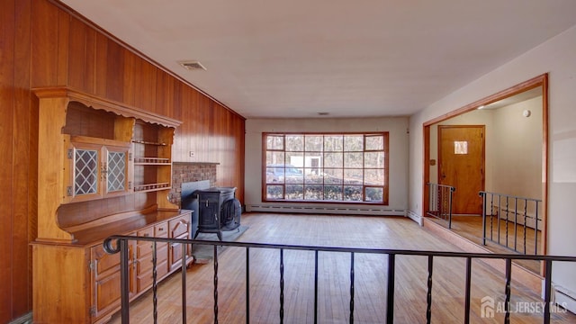 living room featuring visible vents, hardwood / wood-style floors, a wood stove, and a baseboard radiator