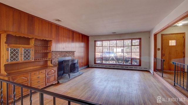 office space with a wood stove, light wood-style floors, visible vents, and a baseboard radiator