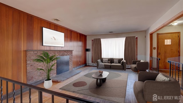 living room featuring wood finished floors, a fireplace, visible vents, and wood walls