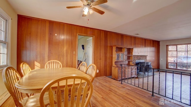 dining area with baseboard heating, wood walls, ceiling fan, and wood finished floors