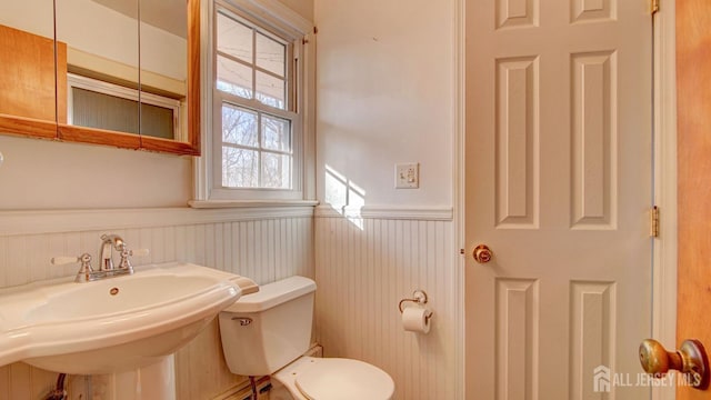 bathroom featuring a wainscoted wall, toilet, and a sink