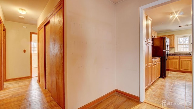 hall with baseboards and light wood finished floors