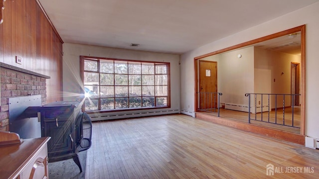 interior space with a baseboard heating unit, wood-type flooring, and visible vents