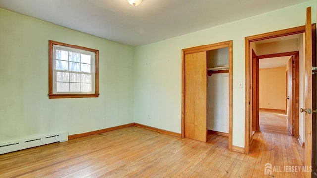 unfurnished bedroom with light wood-type flooring, baseboards, baseboard heating, and a closet