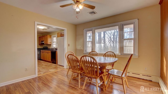 dining space featuring visible vents, light wood-style flooring, baseboards, and ceiling fan