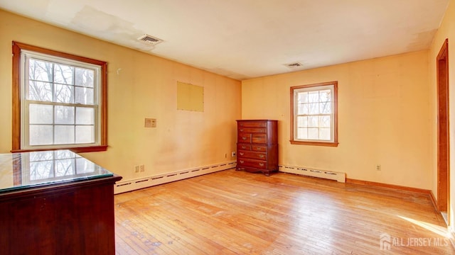 unfurnished bedroom with a baseboard heating unit, visible vents, and light wood-style flooring