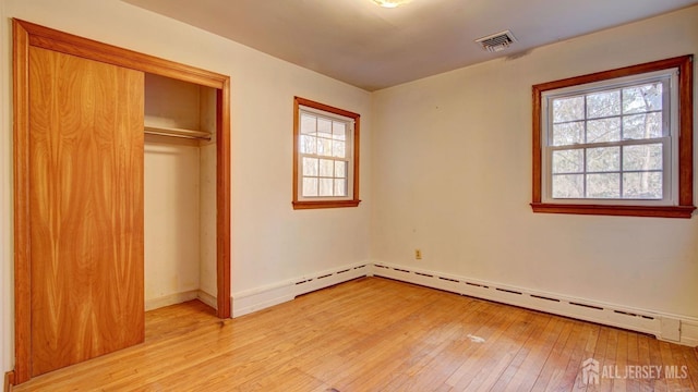 unfurnished bedroom with visible vents, light wood-style flooring, a closet, a baseboard radiator, and baseboards