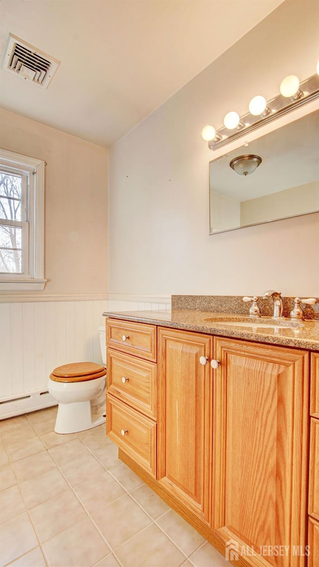 bathroom with a wainscoted wall, visible vents, a baseboard radiator, tile patterned flooring, and toilet