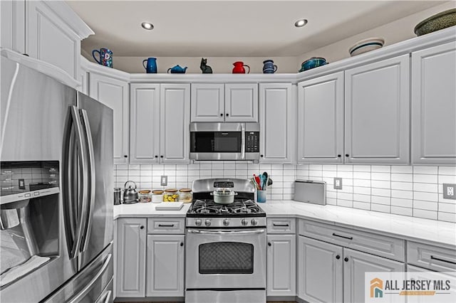 kitchen featuring appliances with stainless steel finishes, decorative backsplash, white cabinetry, and recessed lighting