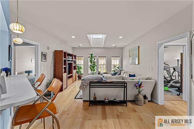 living room with light wood-style flooring, recessed lighting, and a skylight