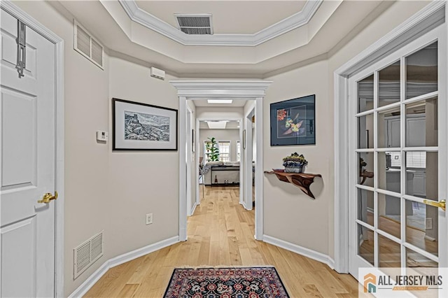 hall with crown molding, light wood-style flooring, and baseboards