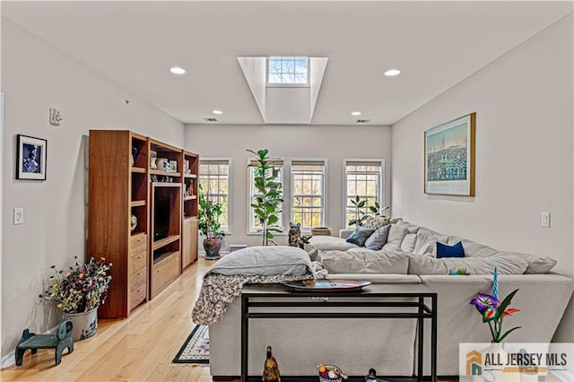 living area with light wood-style flooring, recessed lighting, and a skylight