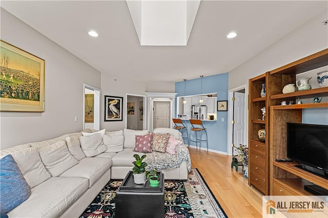 living area with light wood finished floors, recessed lighting, and baseboards