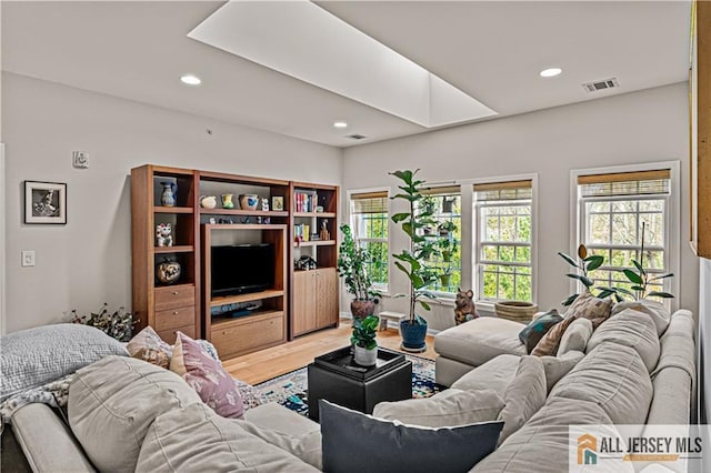 living area with light wood finished floors, recessed lighting, and a skylight